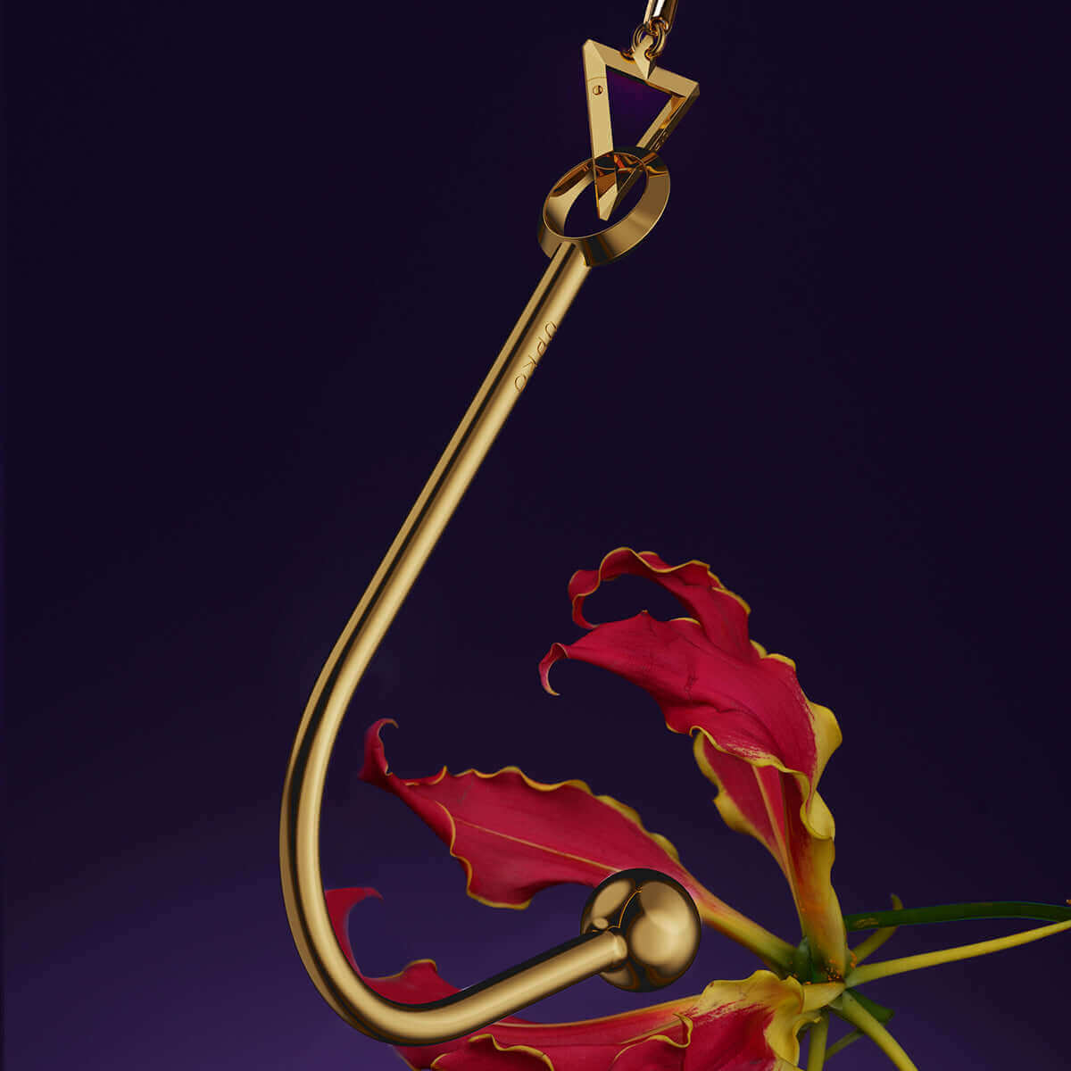 Elegant gold vaginal and anal hook displayed with a vibrant flower, showcasing its unique design and functionality.