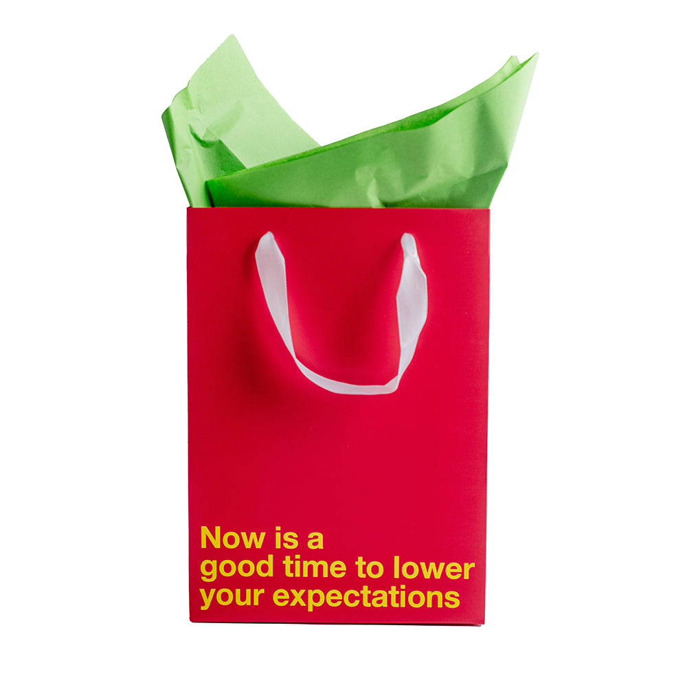 Lower Your Expectations Color Gift Bag Red with humorous text, perfect for gag gifts and white elephant exchanges.