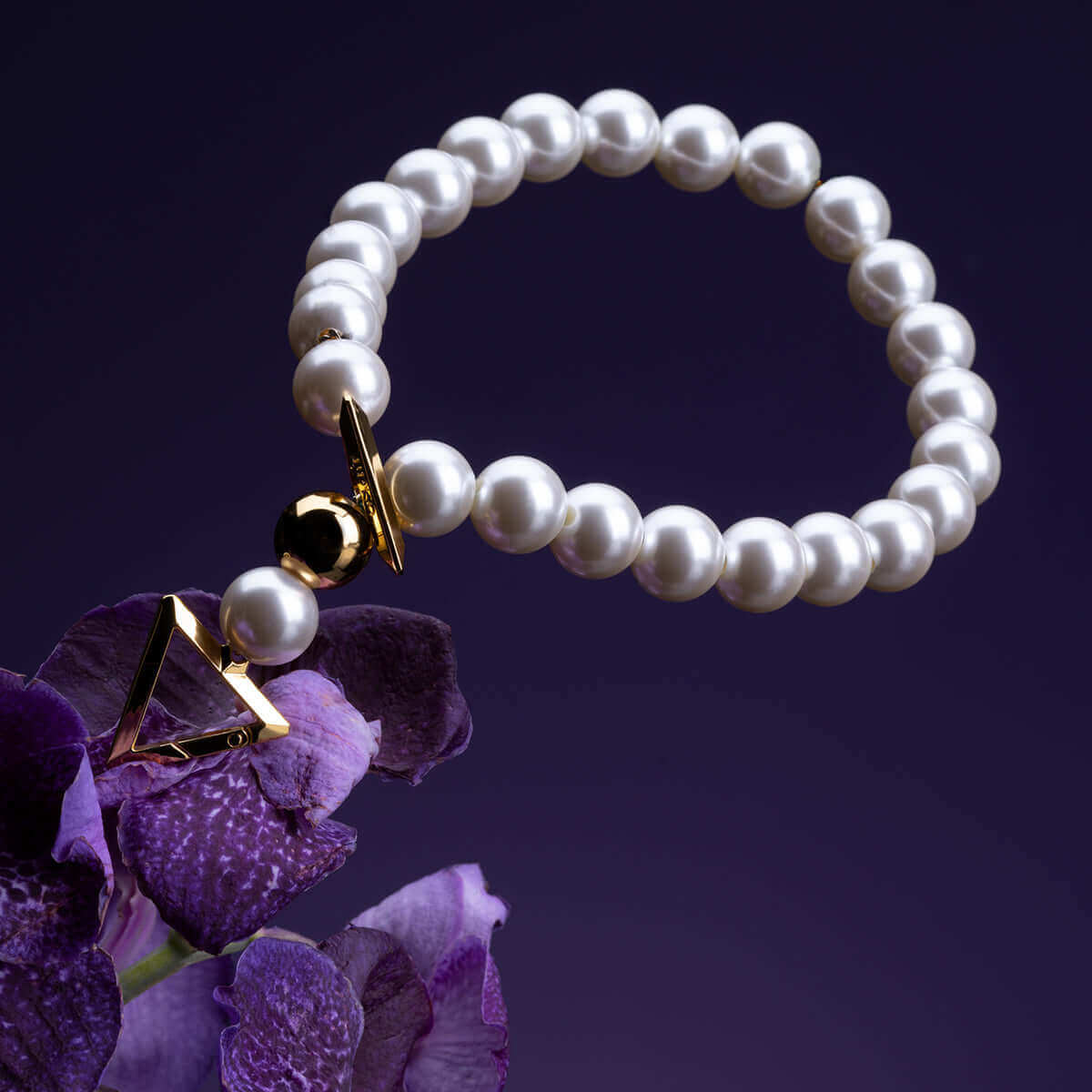 UPKO "Moist Eyes" pearl necklace collar showcasing lustrous pearls and geometric gold accents against a vibrant purple background.