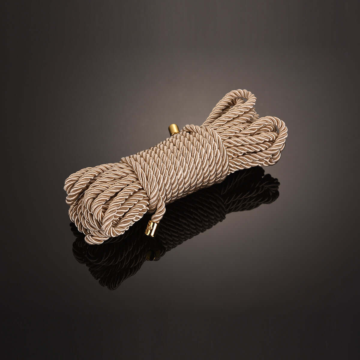 Luxurious gold bondage rope, 32.8 ft in length, ideal for Shibari workshops, displayed on a reflective surface.
