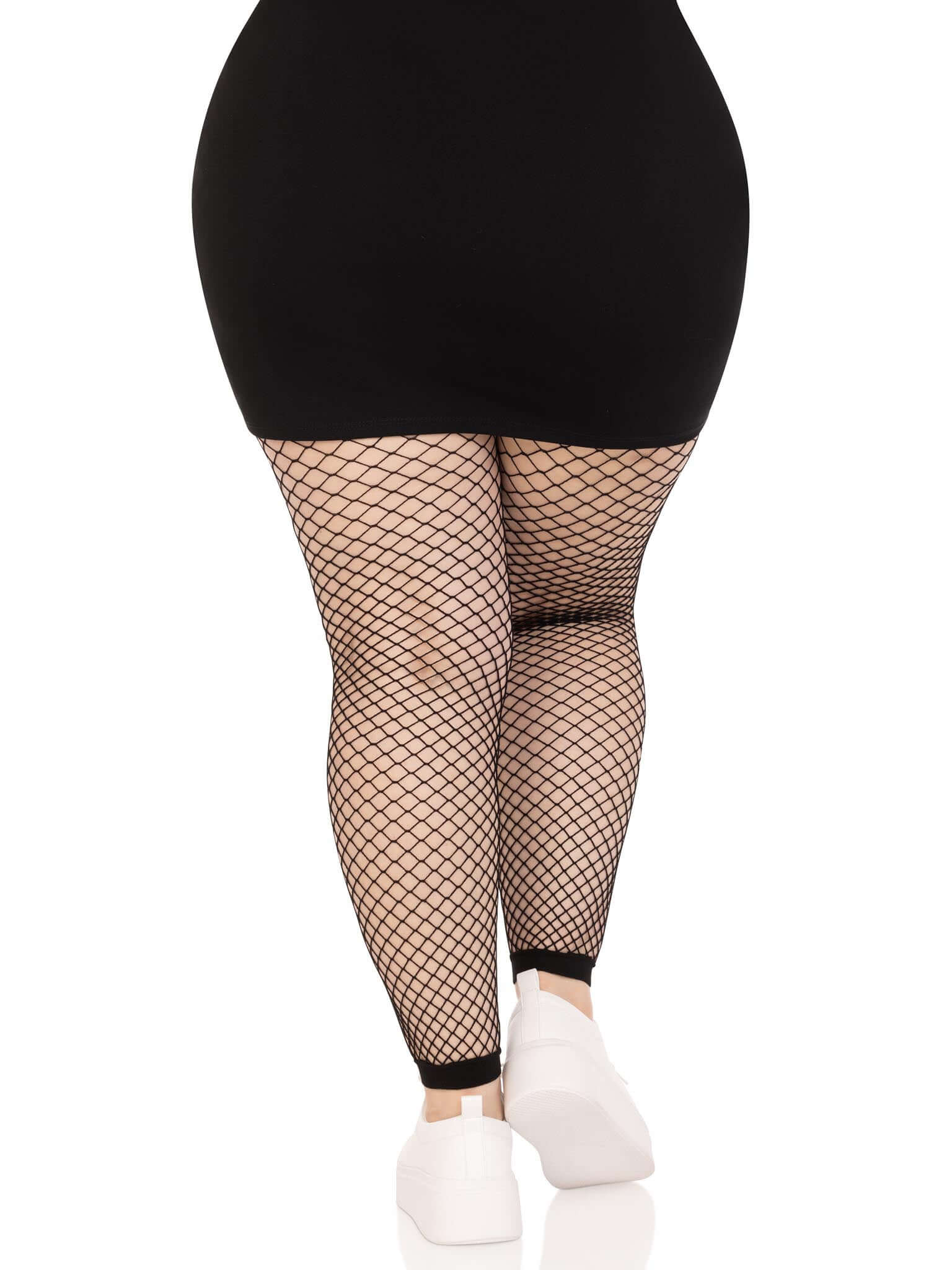 Woman wearing black industrial net footless tights, back view, paired with a black skirt and white shoes, suitable for dress sizes 16-20.
