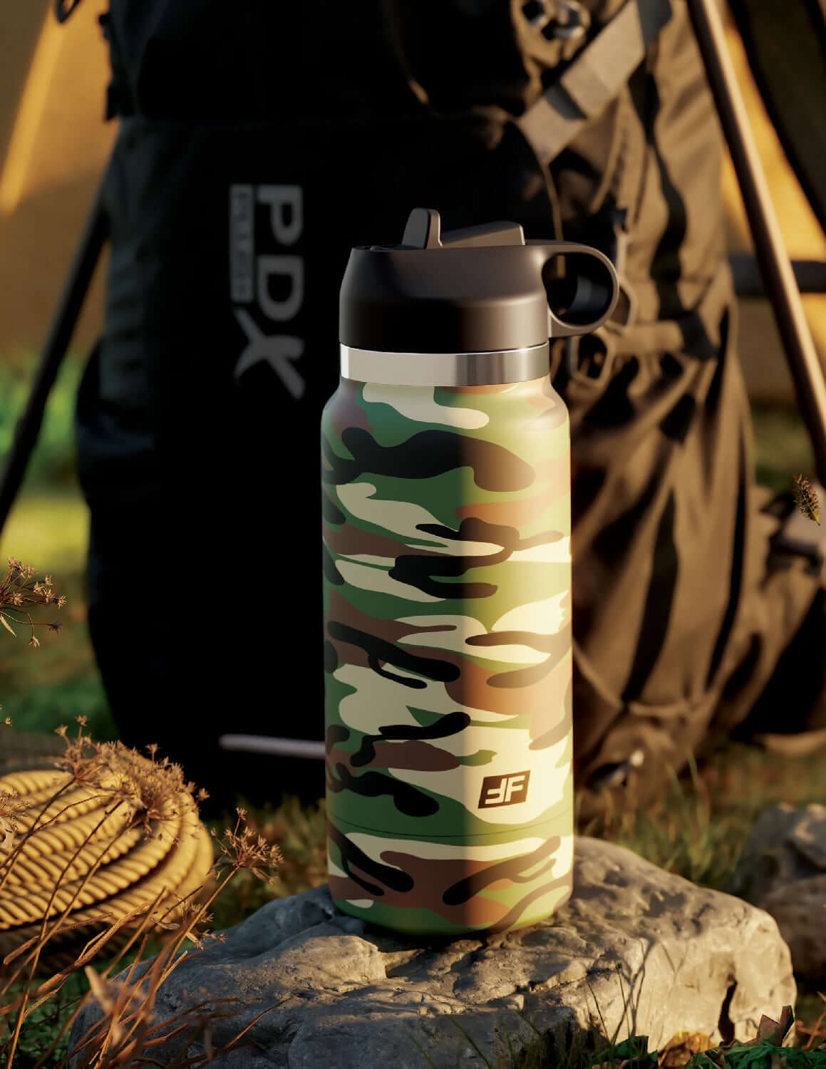 Camo-patterned Fap Flask Happy Camper water bottle stroker placed outdoors near camping gear