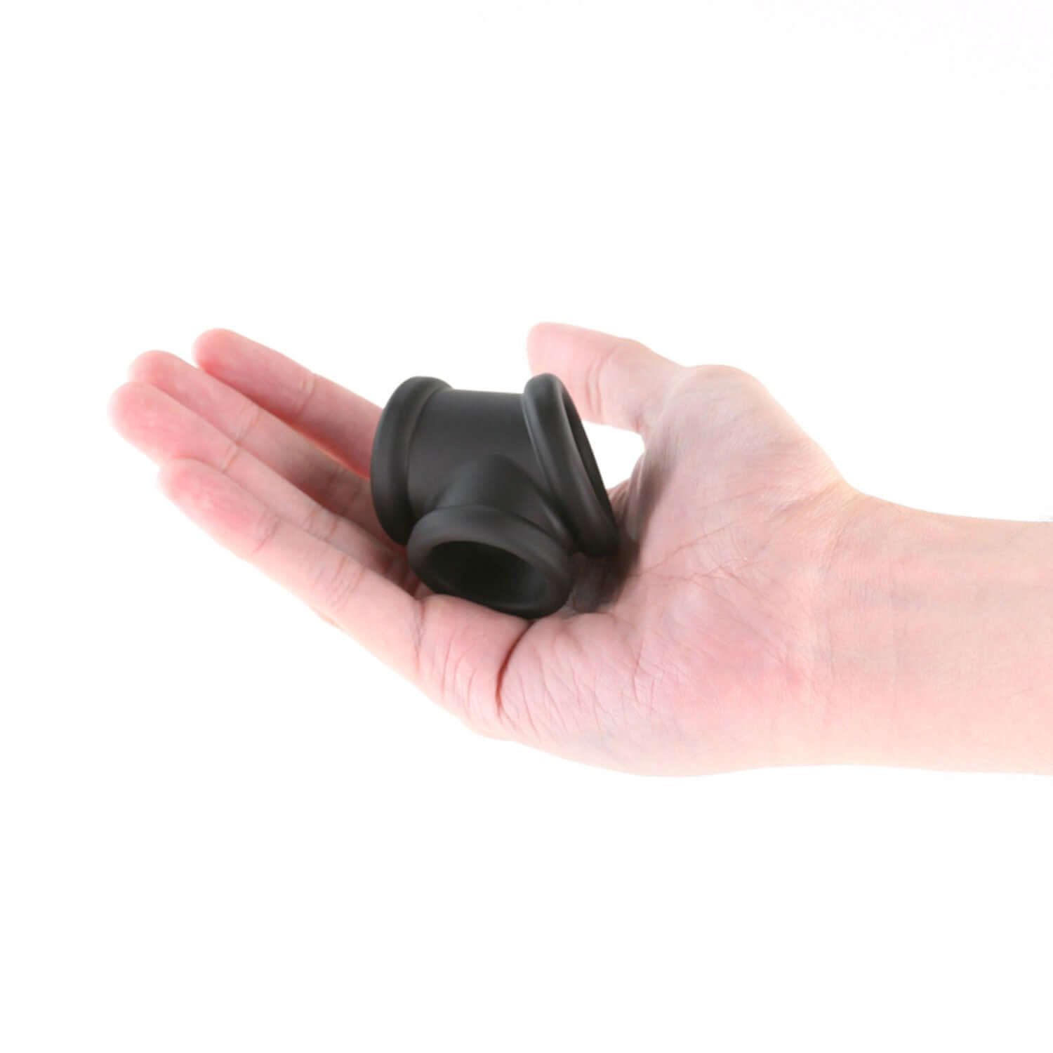 Hand holding Renegade - Piper - Black silicone cock and ball ring for prolonged performance enhancement.