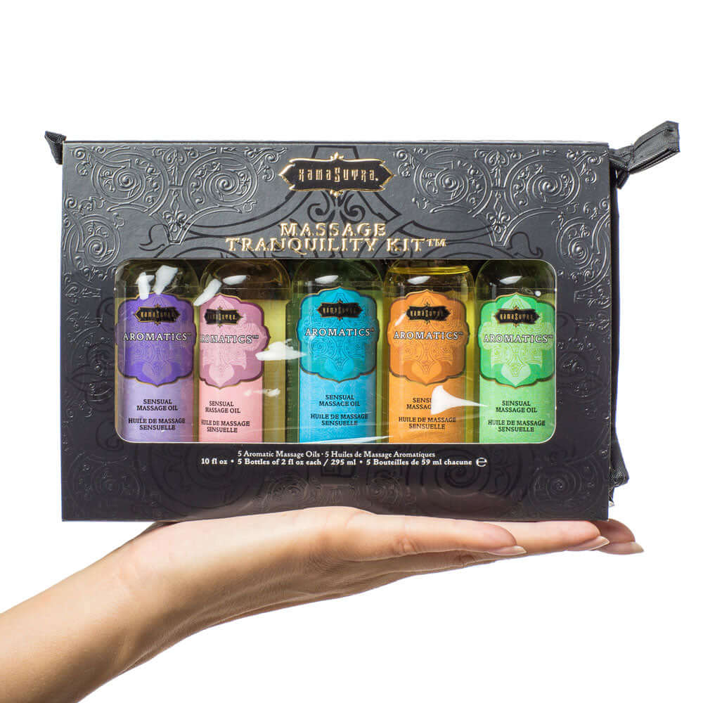 Kama Sutra Massage Tranquility Kit holding by a hand, featuring five Aromatics Massage Oil blends in travel-friendly packaging.