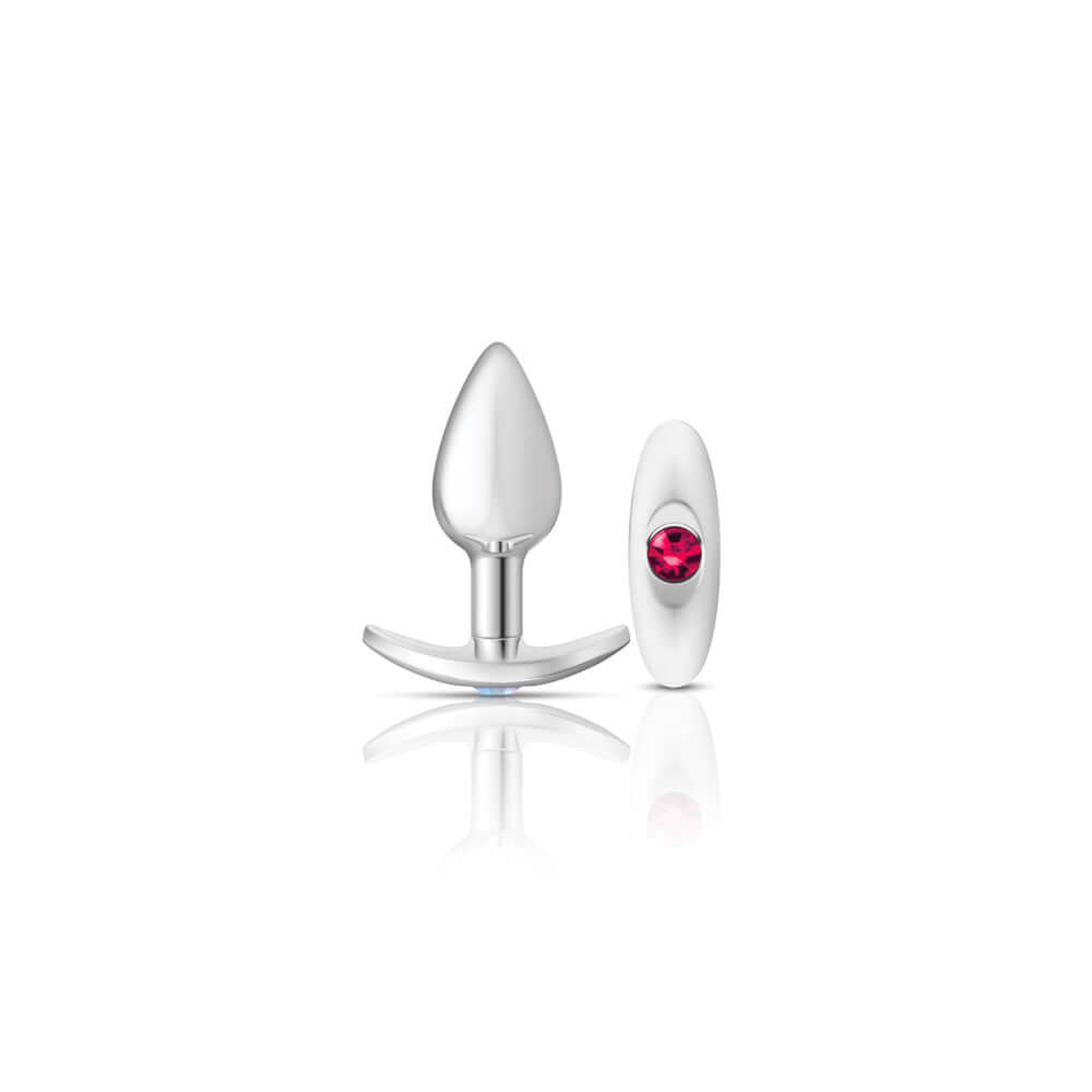 Silver metal butt plug kit with bright pink gemstone, featuring a teardrop shape and interchangeable anchor bases.