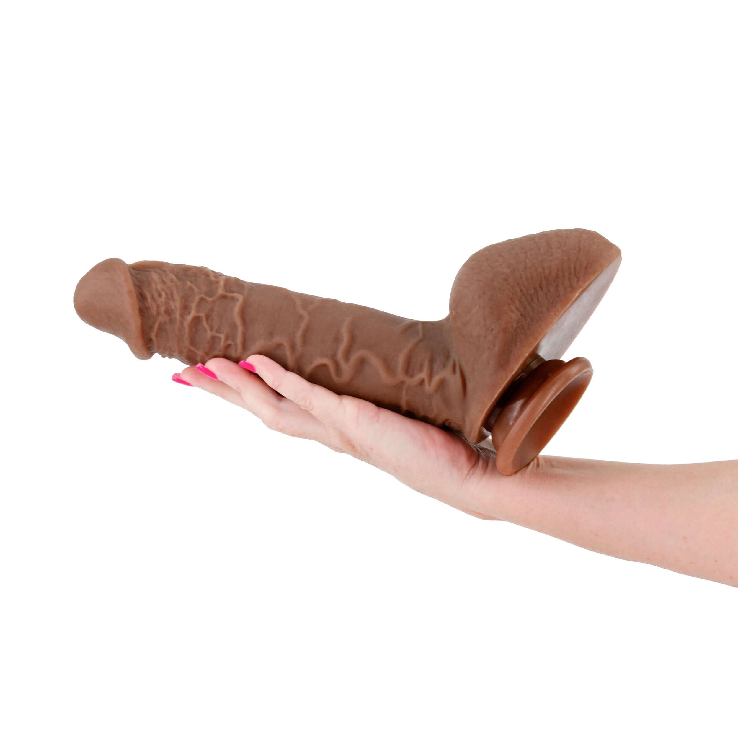 Hand holding Shane Diesel Dual Density Brown Dildo with suction cup base and realistic texture.