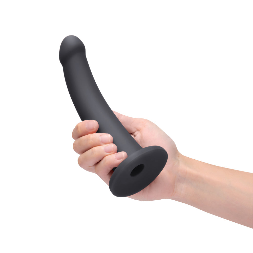 B-Vibe Essentials 7 Inch Smooth Silicone Dildo Black held in hand against a white background.