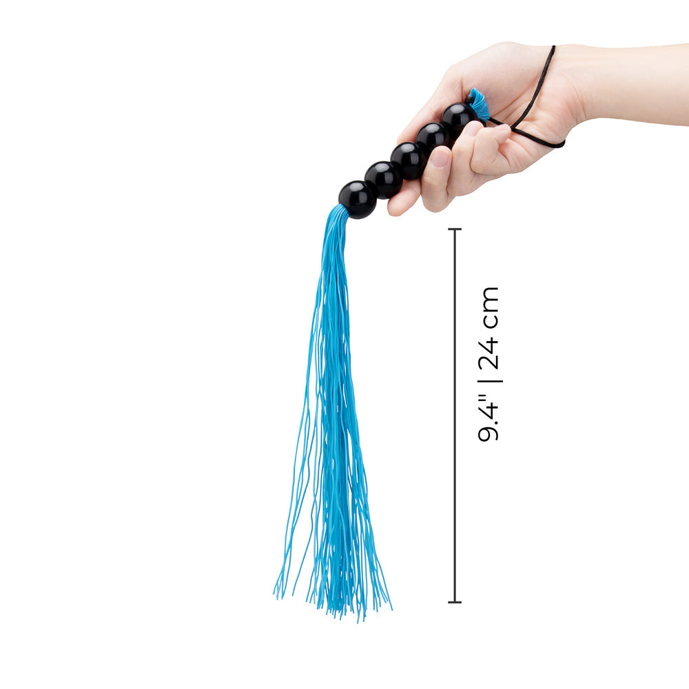 B-vibe Essentials Beaded Flogger in hand showcasing the blue tassels and beaded handle design.