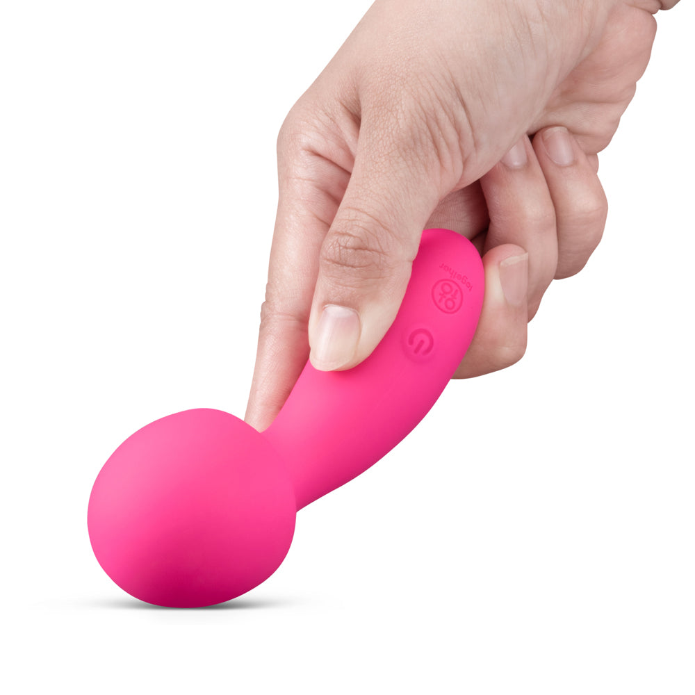Hand holding the Together Spark On The Go Mini Wand Vibrator in pink, designed for portable pleasure.