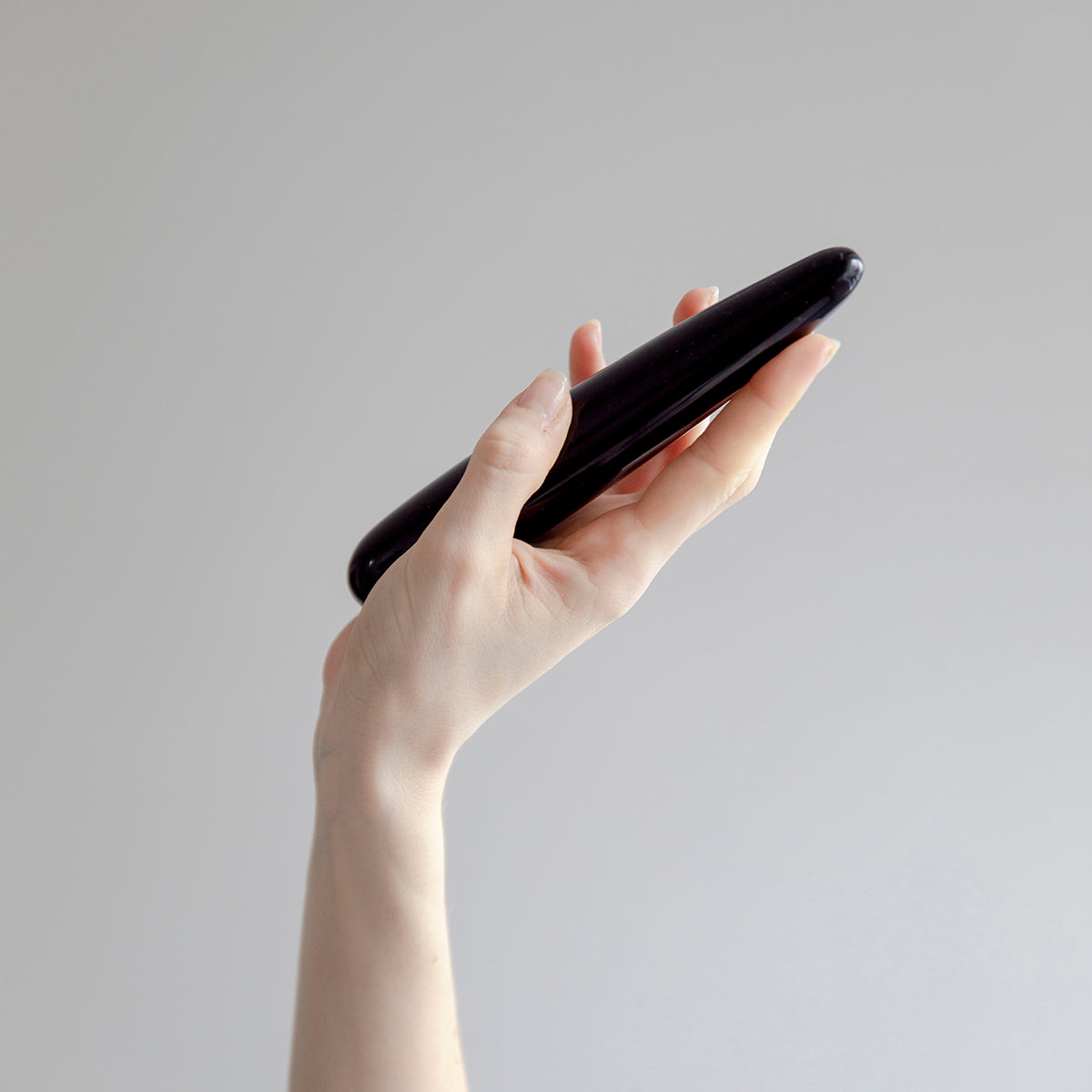 Chakrubs Xaga Slim Non-Phallic Dildo held in hand against a minimalist background.