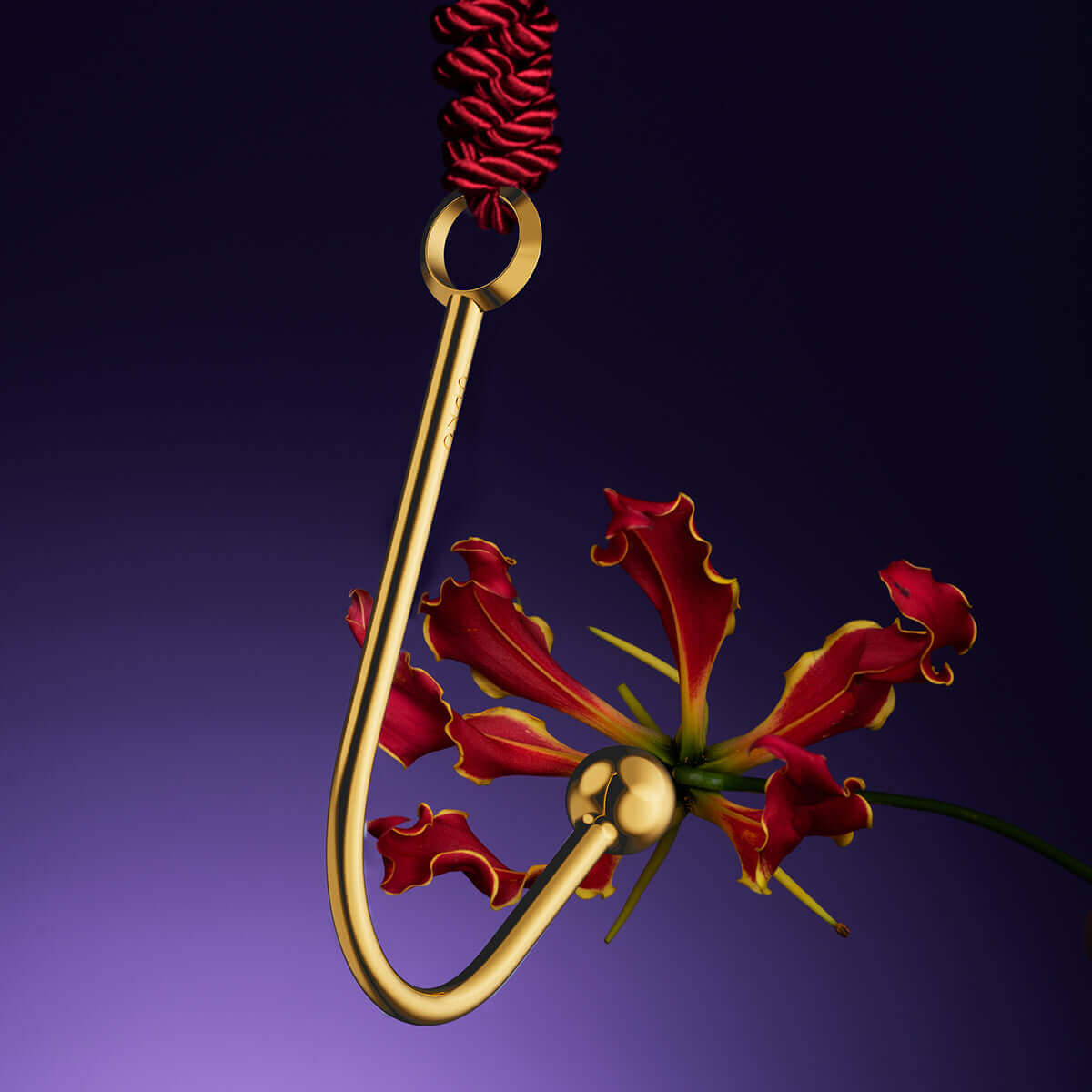 UPKO vaginal/anal hook in gold, featuring a ball end and a decorative flower, against a purple background.