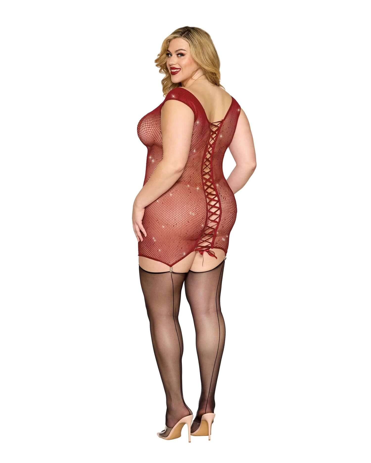 Plus size model wearing Garter Slip DMND in red with lace-up back detail, paired with sheer black stockings.