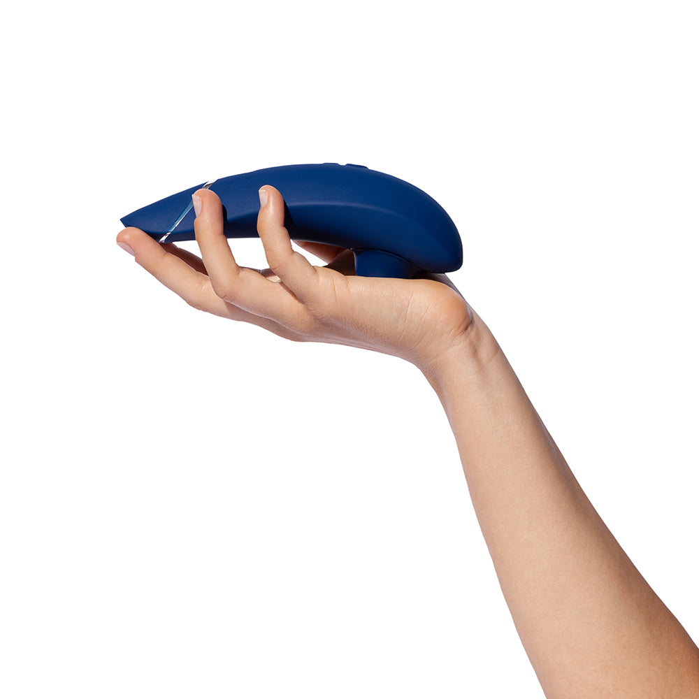 Womanizer Premium 2 Pleasure Air Clitoral Stimulator Blueberry held in a hand against a white background.