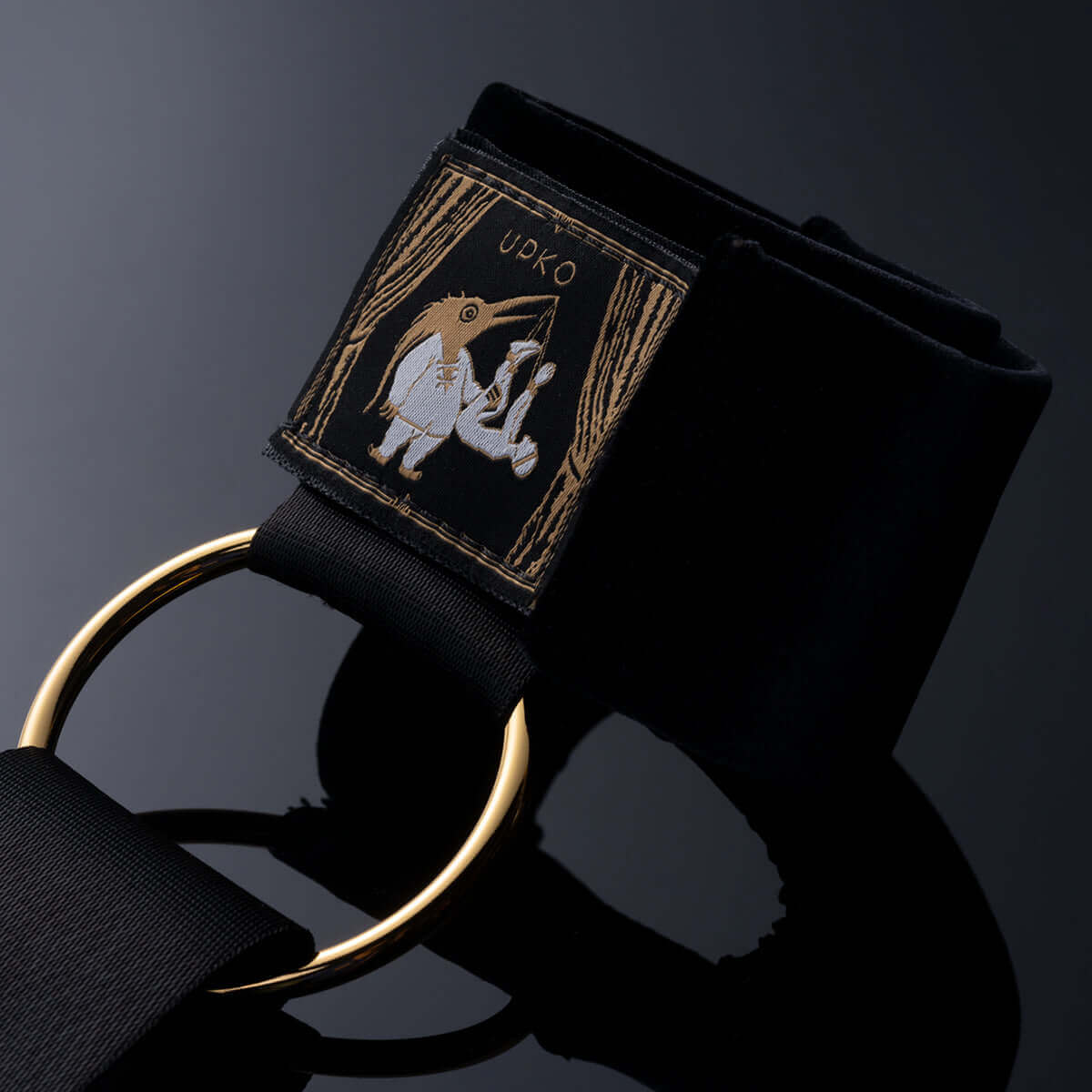 UPKO bondage gear sling with cuffs featuring a gold ring and embroidered design on silky fabric.
