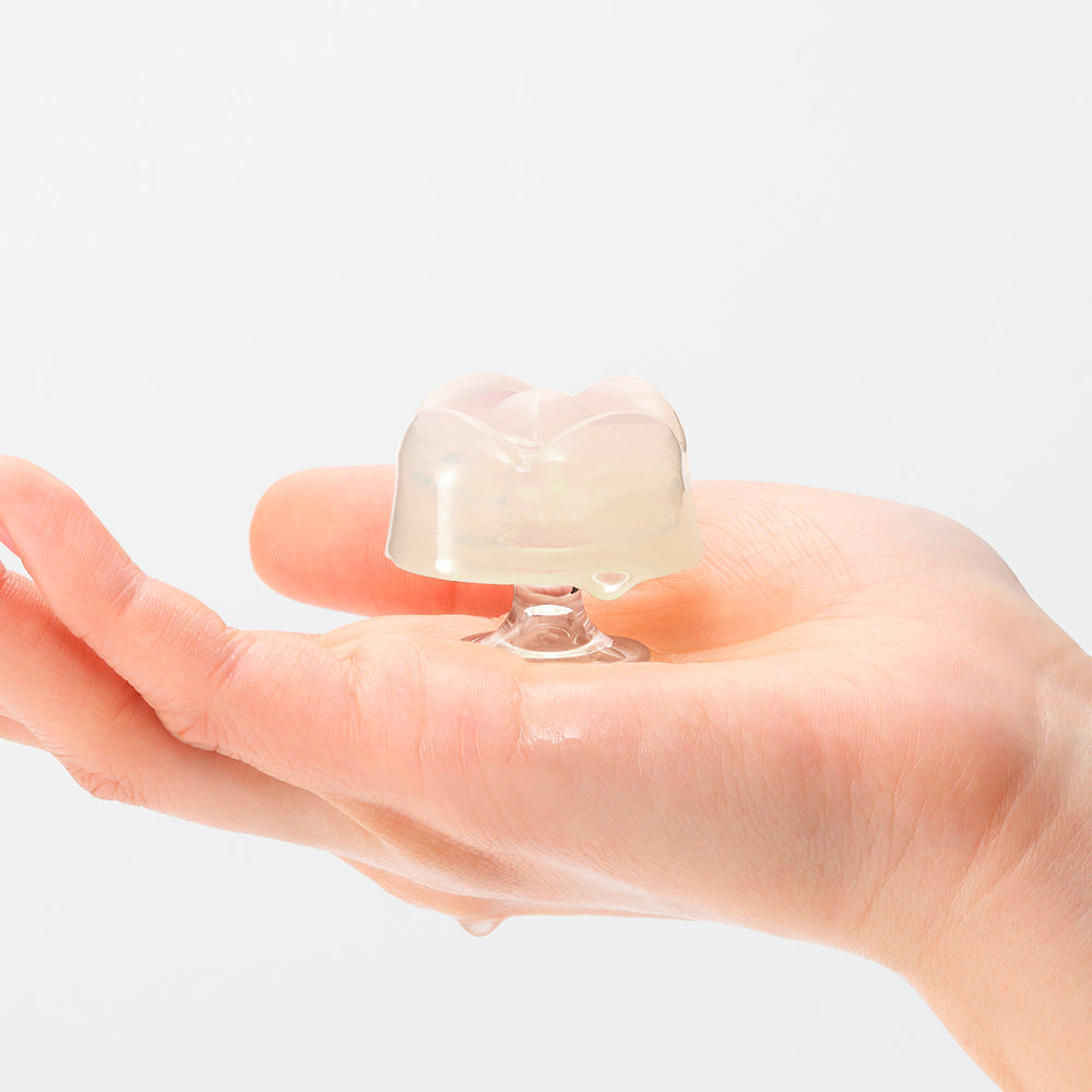 Iroha Petit Lily Disposable Clitoral Stimulator Clear resting on a hand, showcasing its unique shape and texture.