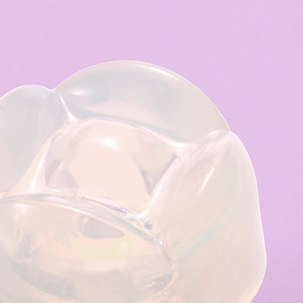 Iroha Petit Lily Disposable Clitoral Stimulator Clear close-up on a purple background.
