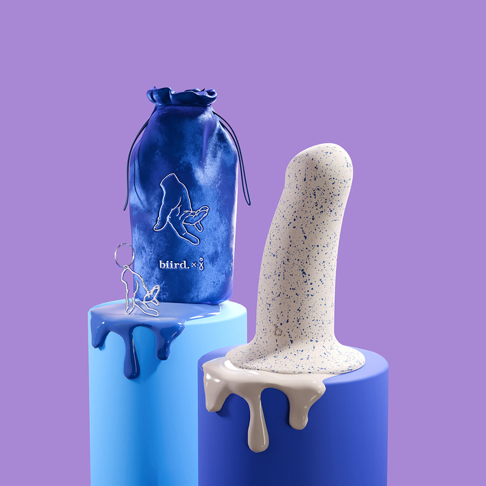 Biird Boo 5.5 Inch Soft Silicone Suction Cup Dildo Blue displayed alongside a pouch and accessory on colorful pedestals.
