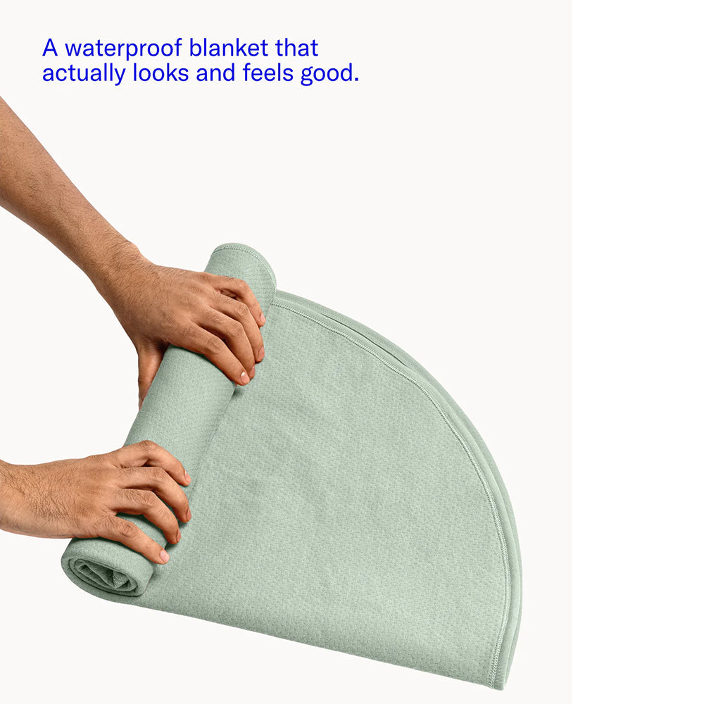 Dame Thro Waterproof Sex Blanket Sage being rolled up, showcasing its soft and stylish design.