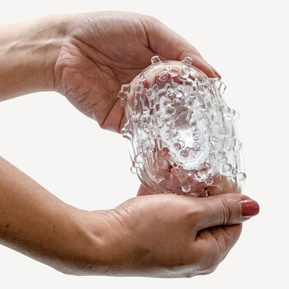 Hands holding The Handy TrueGrip Gen 2 Masturbator Sleeve Clear, showcasing its unique textured design.