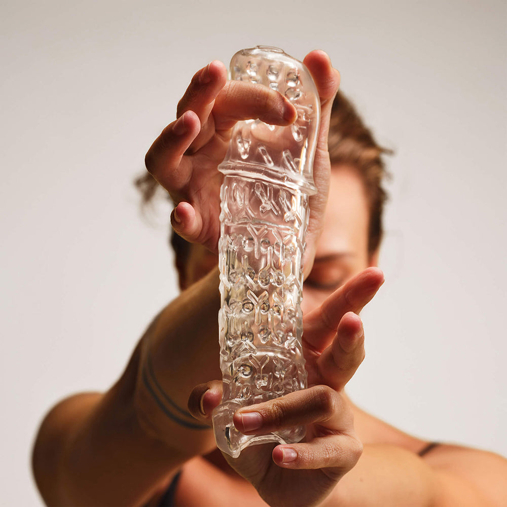 The Handy TrueGrip Gen 2 Masturbator Sleeve Clear held in hand showcasing its texture and design features.