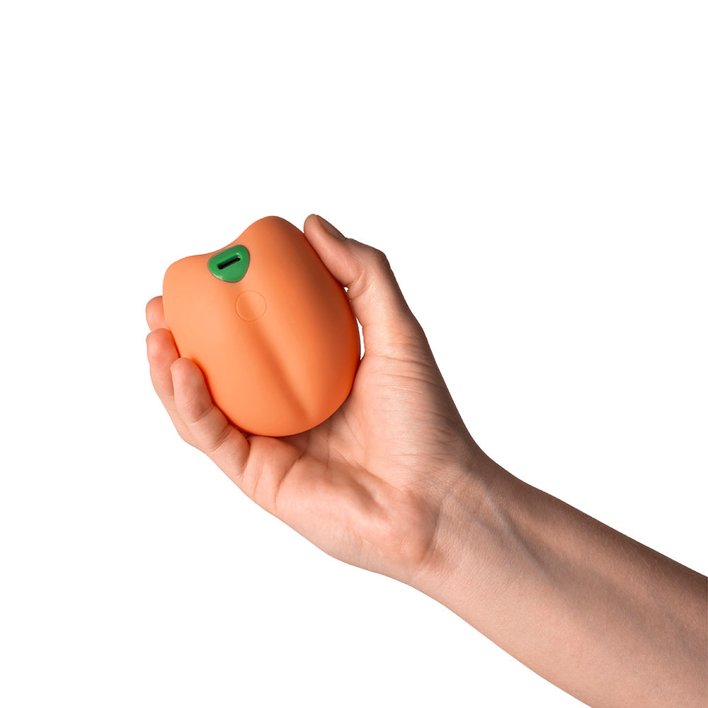 Emojibator Peach Vibrating Stroker held in a hand, showcasing its compact design and vibrant color.