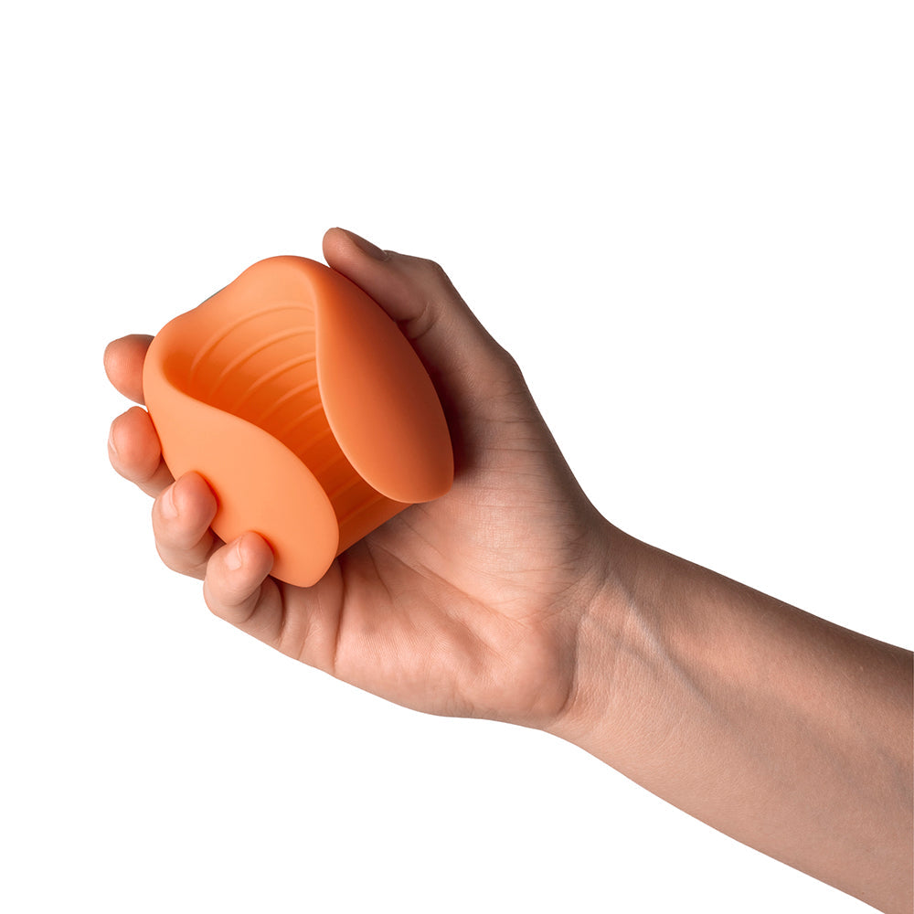Person holding the Emojibator Peach Vibrating Stroker in hand, showcasing its compact design and soft silicone texture.