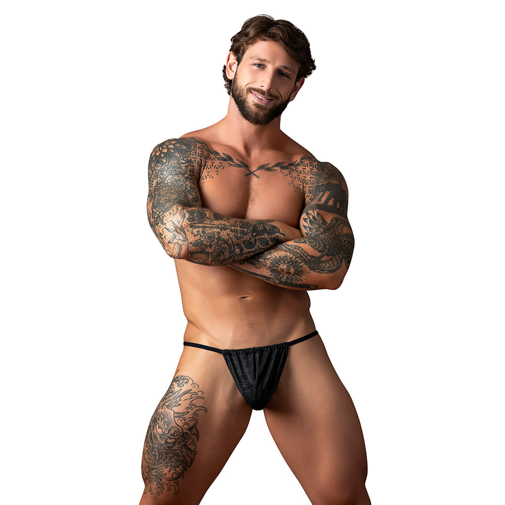 Male Power Kilauea Limited Edition G-String Black One Size displayed on a muscular man with tattoos.