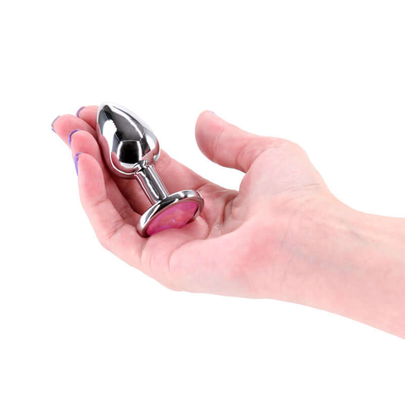 Rear Assets Silver Anal Plug Medium Pink Gem held in hand with a chrome finish and pink gem base.