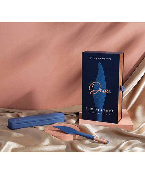 Deia Vibrating Feather Tickler with Charging Case Navy displayed on a soft surface alongside its elegant packaging.