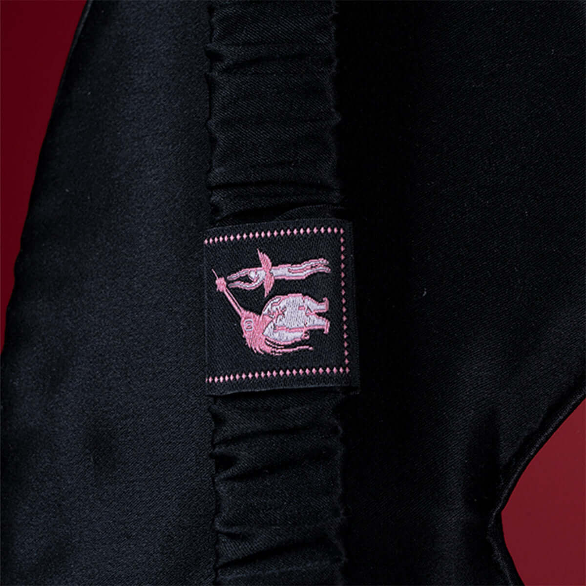 Close-up of UPKO embroidered silk blindfold showing detailed logo on soft black mulberry silk fabric.