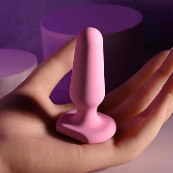 Selopa petite pink silicone anal plug held in hand, rounded tip and flared base for safety, waterproof design