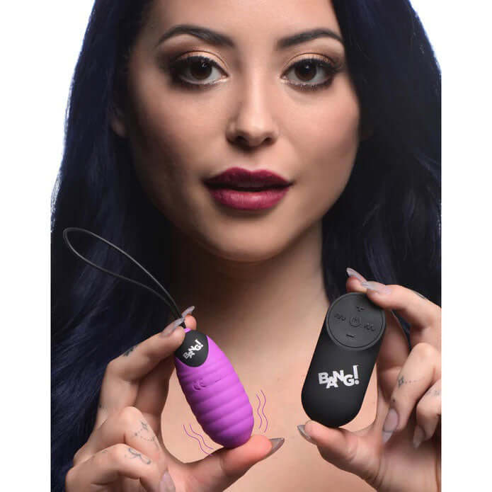 Model showcasing Bang 28x Ribbed Silicone Egg Vibrator Purple and its remote for enhanced pleasure.