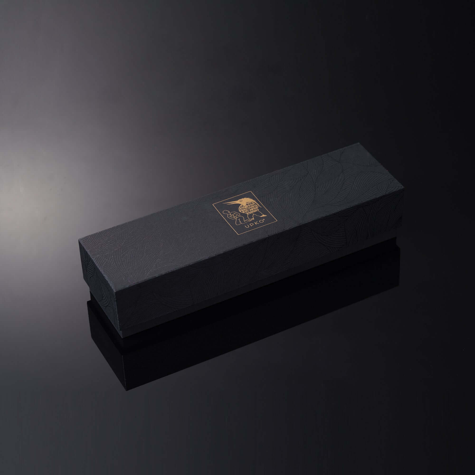 Elegant black packaging box with gold logo for a luxury leather restraint set displayed on a reflective surface.