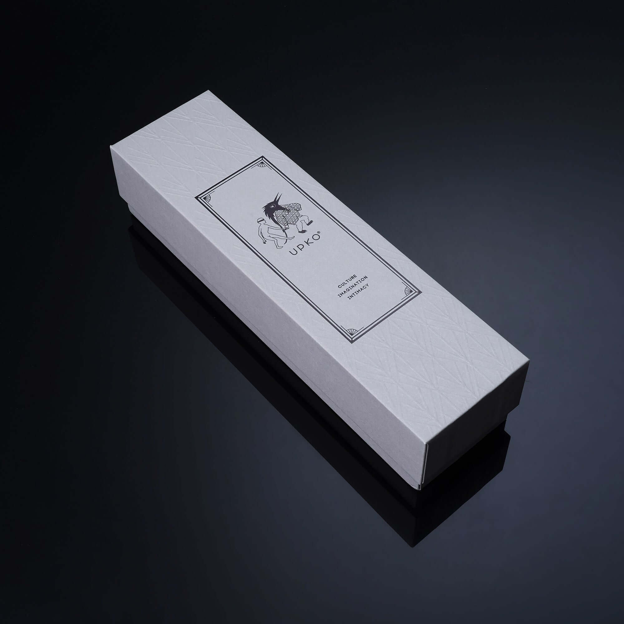 White box packaging for a product with elegant design and logo on a sleek black surface.