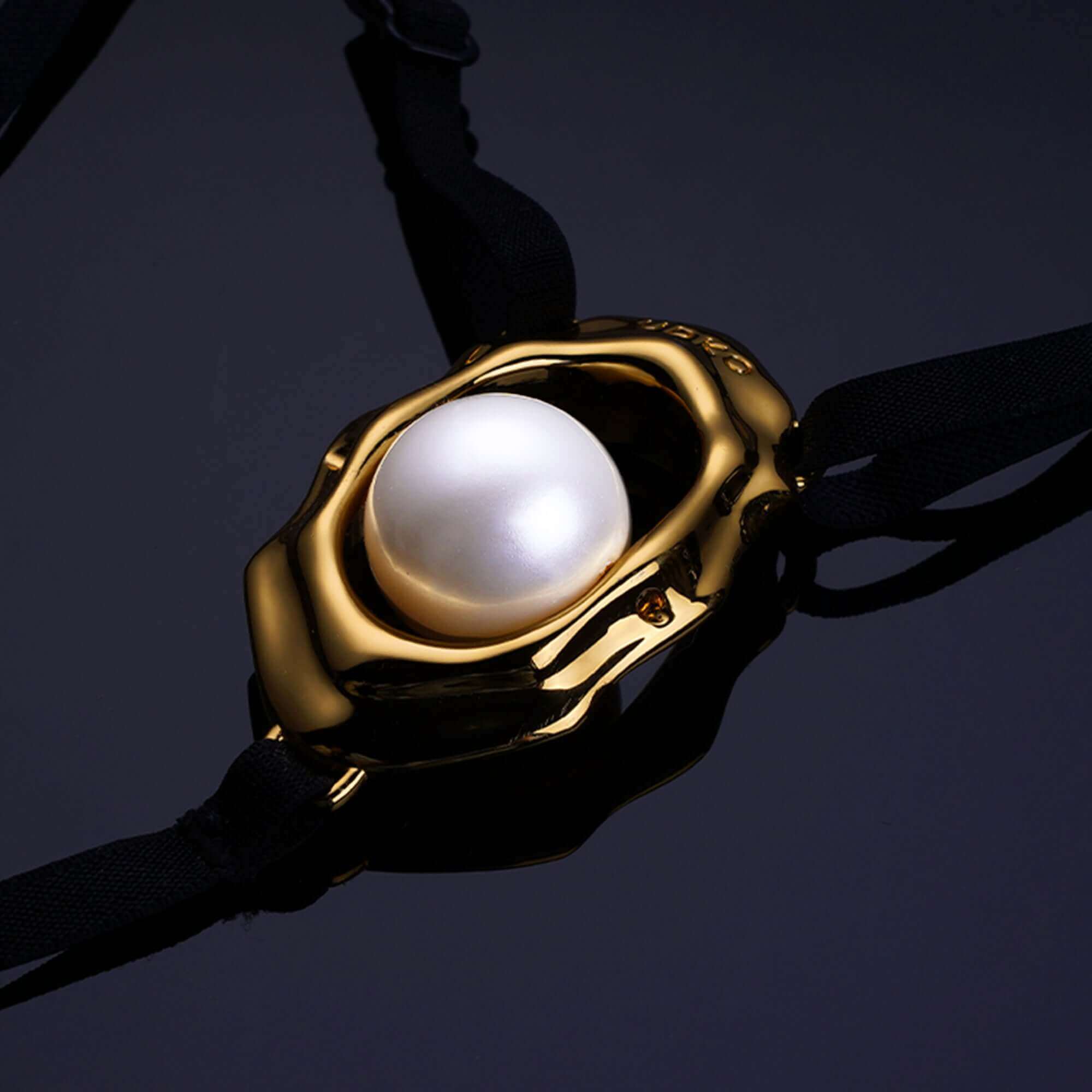 "Close-up of Moist Eyes G-string Clitoral Jewelry featuring gold seashell design and central bead stimulator."