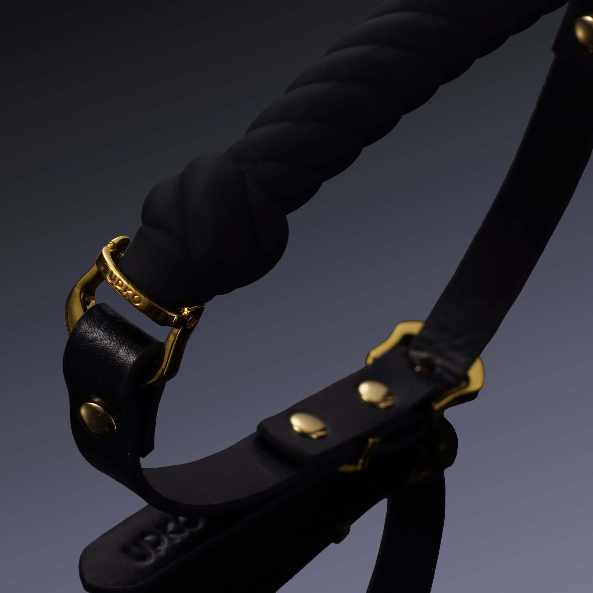 Black UPKO knot-shaped mouth gag with gold hardware, featuring premium silicone and Italian leather for luxury and secure fit.