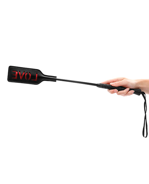 A hand holding the Shots Ouch Love Crop Large Black, showcasing its sleek design and striking rectangular surface.