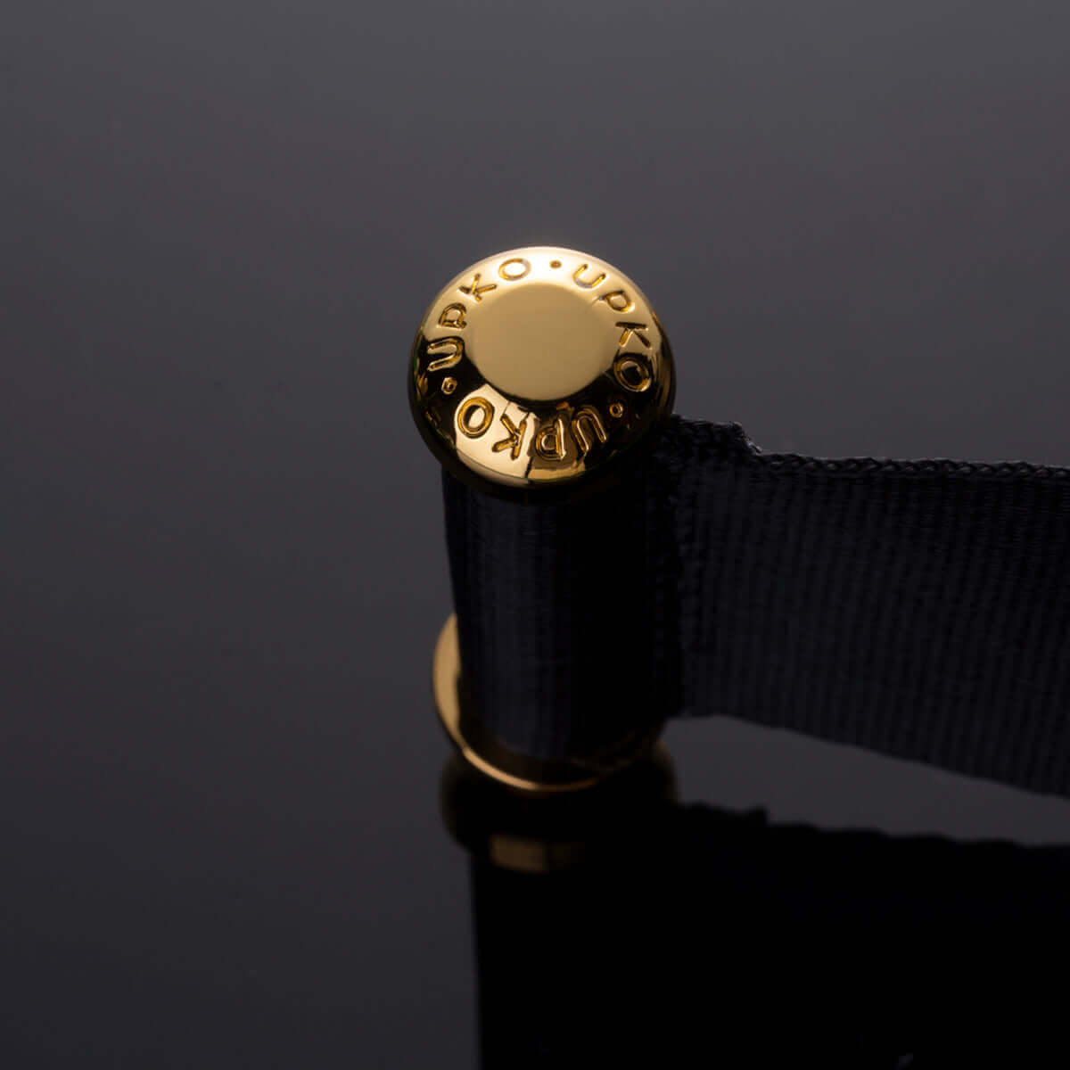 UPKO ankle restraint strap with gold logo on black fabric for S&M and bondage experiences.