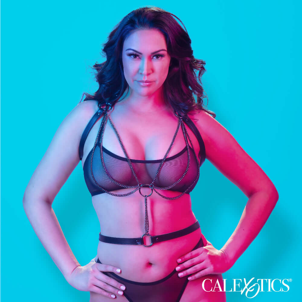 Plus size model wearing Euphoria Collection black multi-chain halter harness in front of blue and pink background.