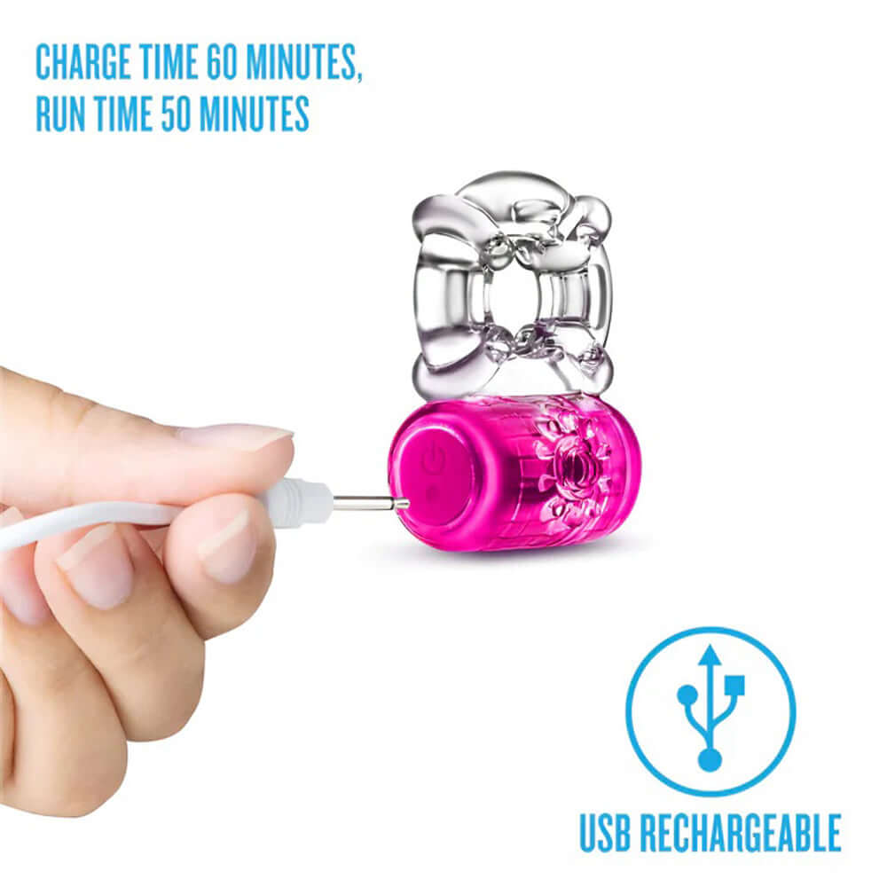 Play With Me Pleaser Rechargeable C-Ring in pink being charged via USB, featuring a sleek design for enhanced pleasure.