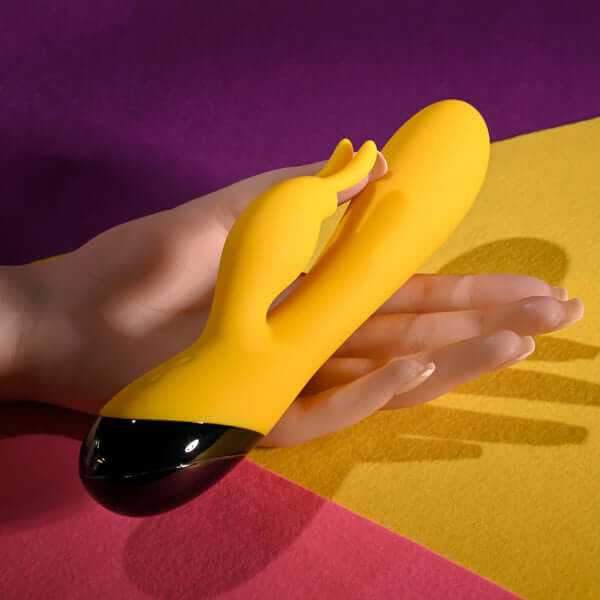 Selopa Buzzz Bunny yellow silicone rabbit vibrator in hand, featuring flexible design and dual motors.