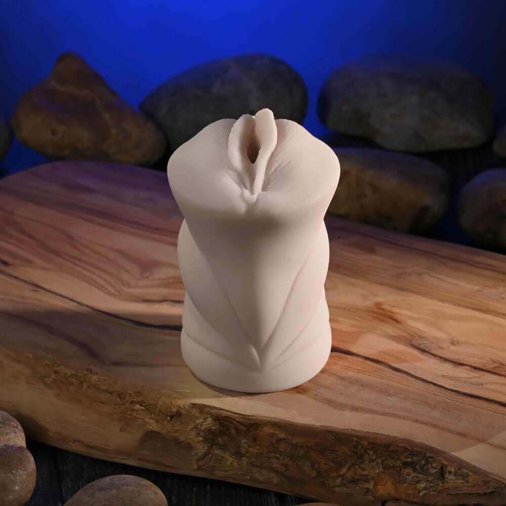 Sasha Grey Movie With Mini Vagina Stroker displayed on a wooden surface with natural stones in the background.