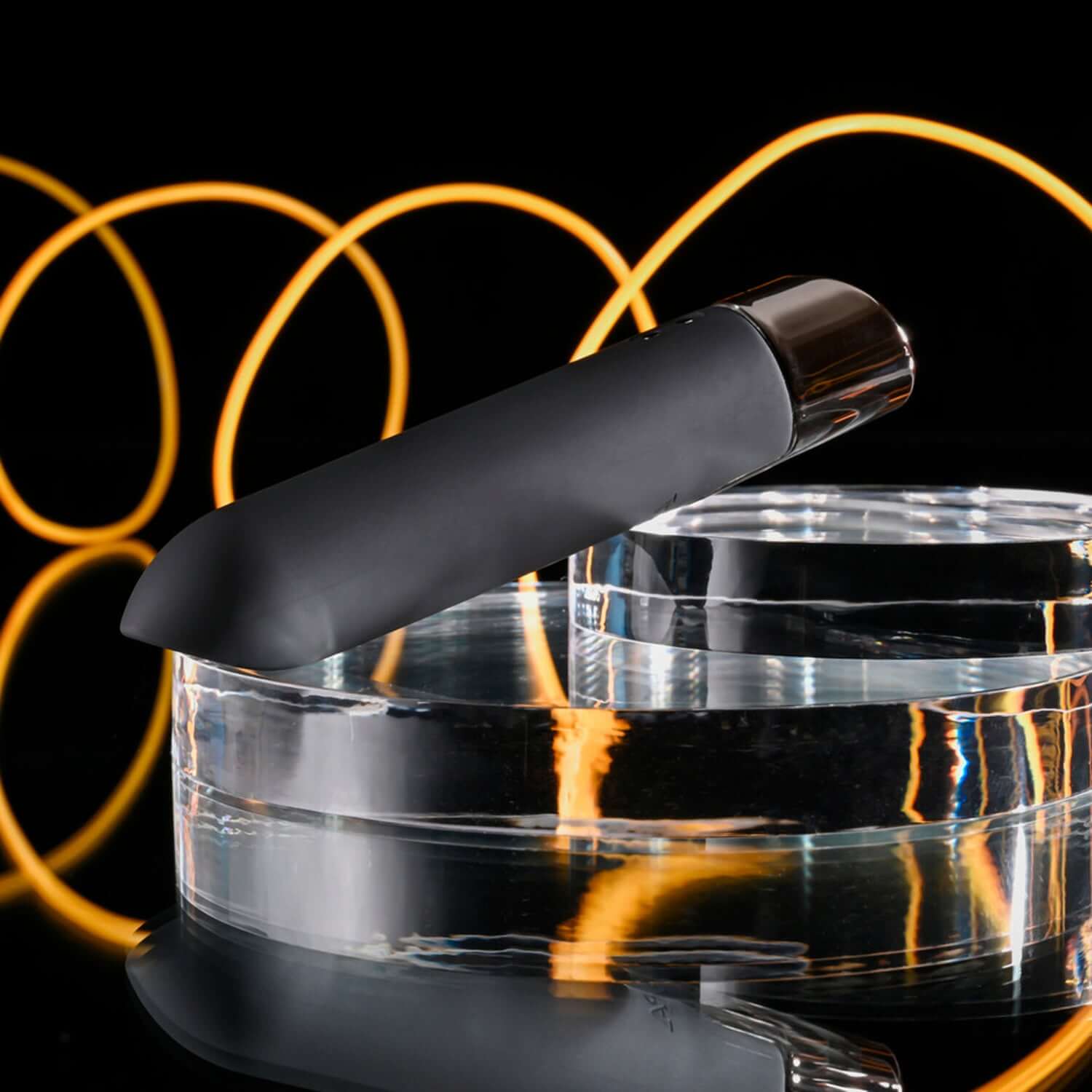 Little Buddy Bullet Vibrator in black with chrome finish on glass surface, featuring sleek, angled tip and vibrant background.