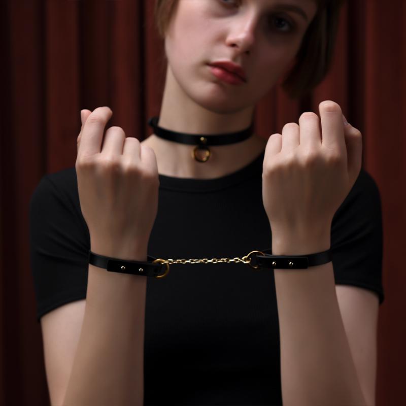 Young woman showcasing UPKO luxury black leather handcuff bracelets with gold chain, exuding elegance and style.