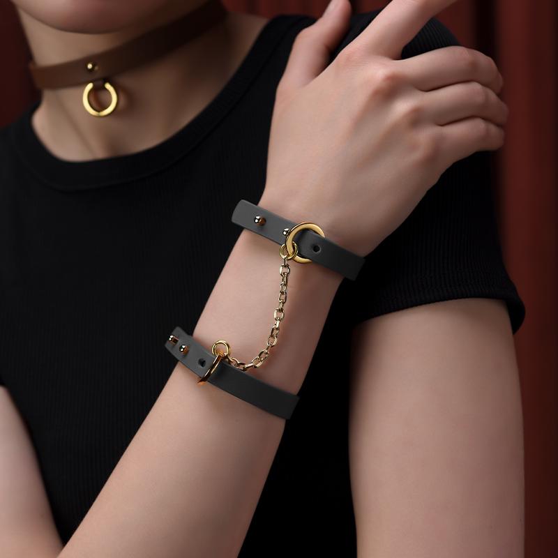 Elegant black leather handcuff bracelets with gold accents worn by a model, showcasing a chic and subtle accessory style.